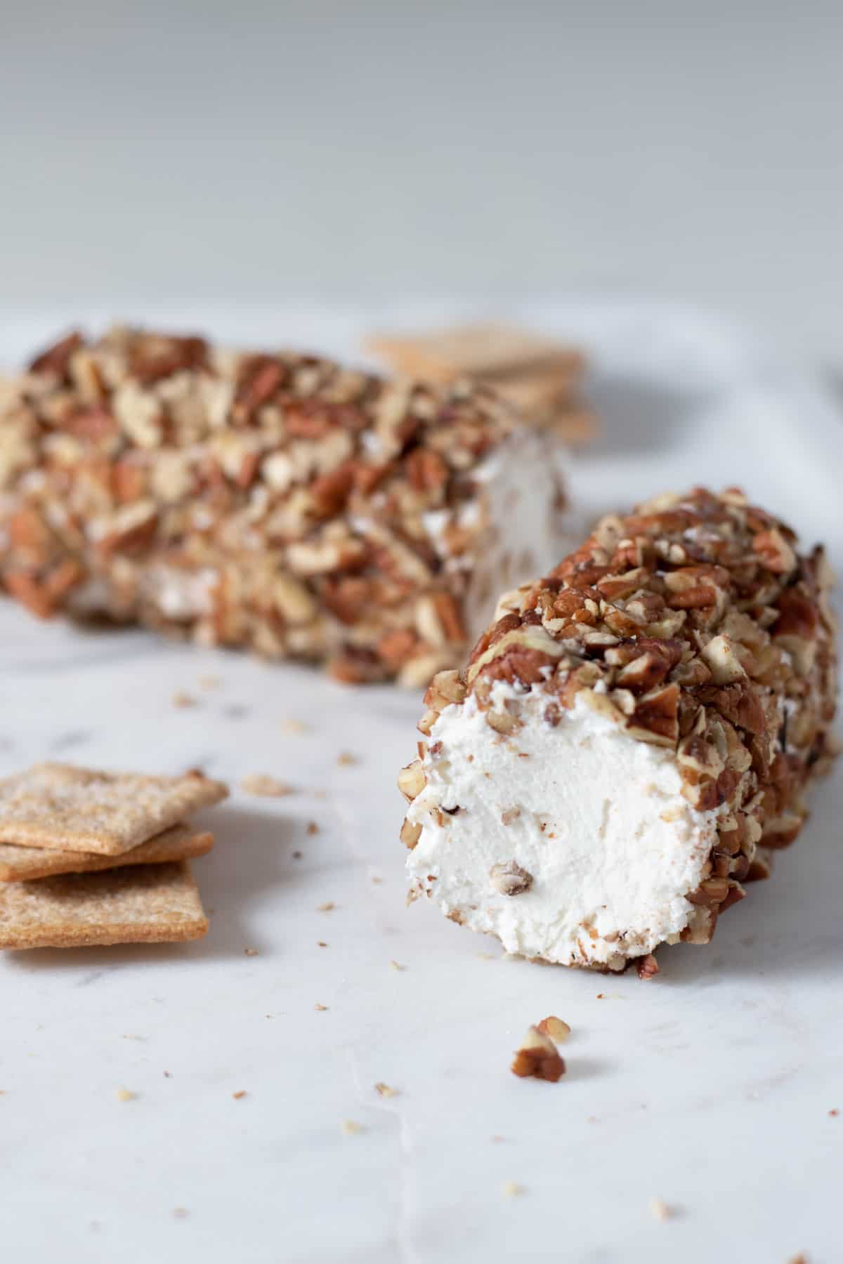 Pecan crusted goat cheese on a marble board with crackers.