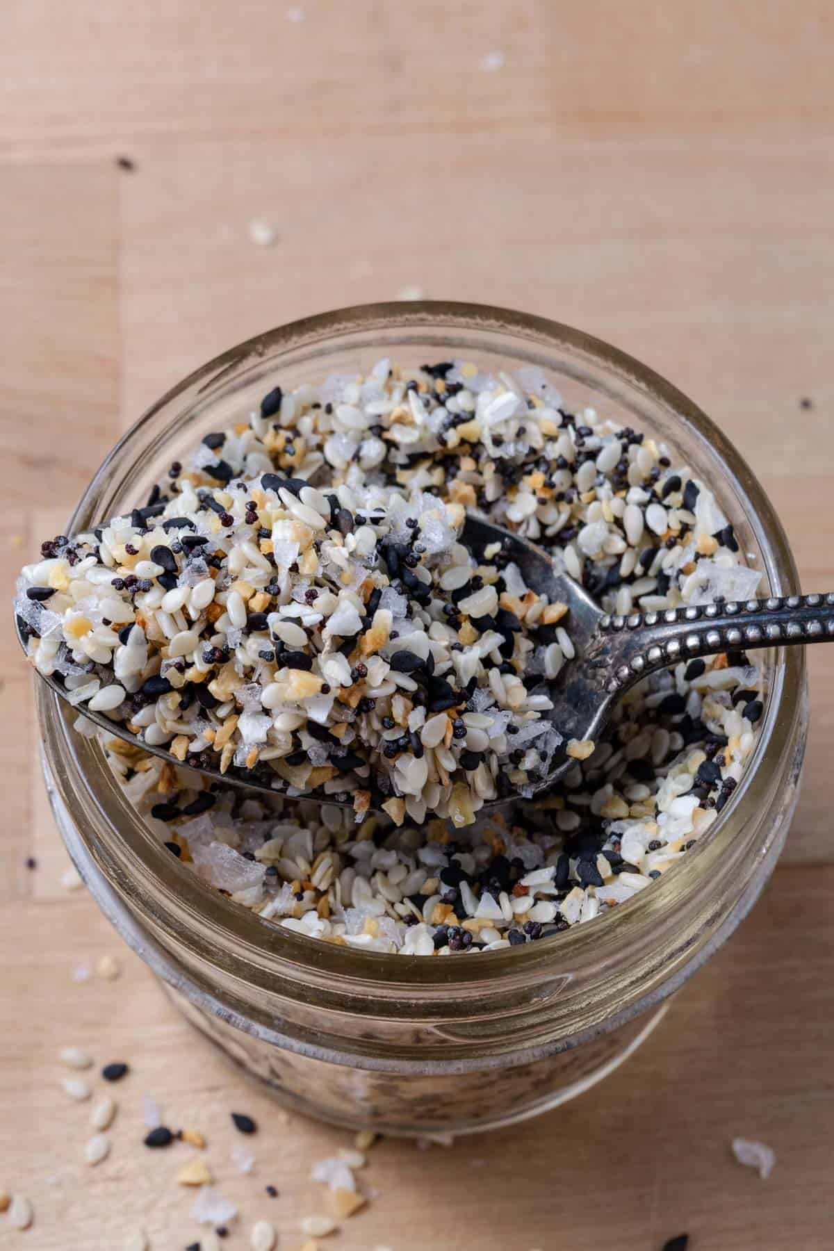 Spoonful of everything bagel seasoning on a glass jar.