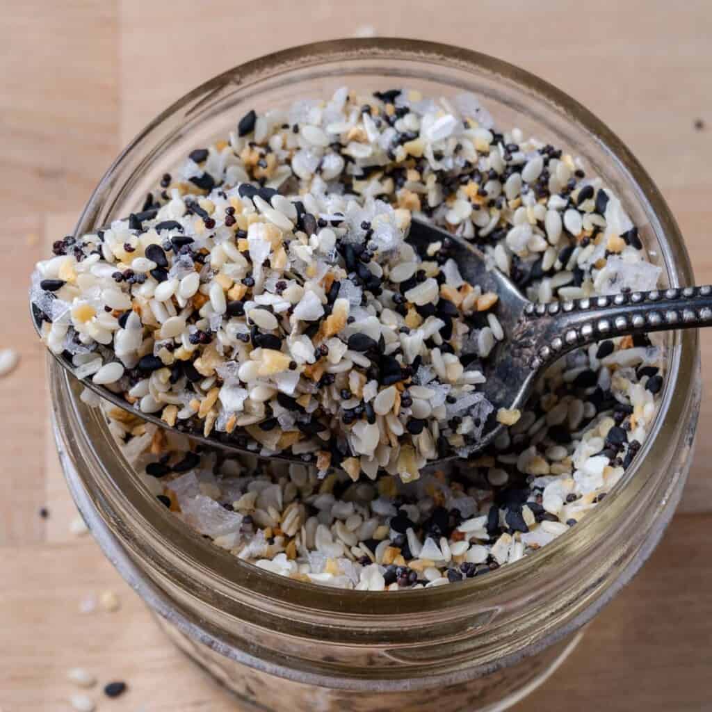 Spoonful of everything bagel seasoning on a glass jar.