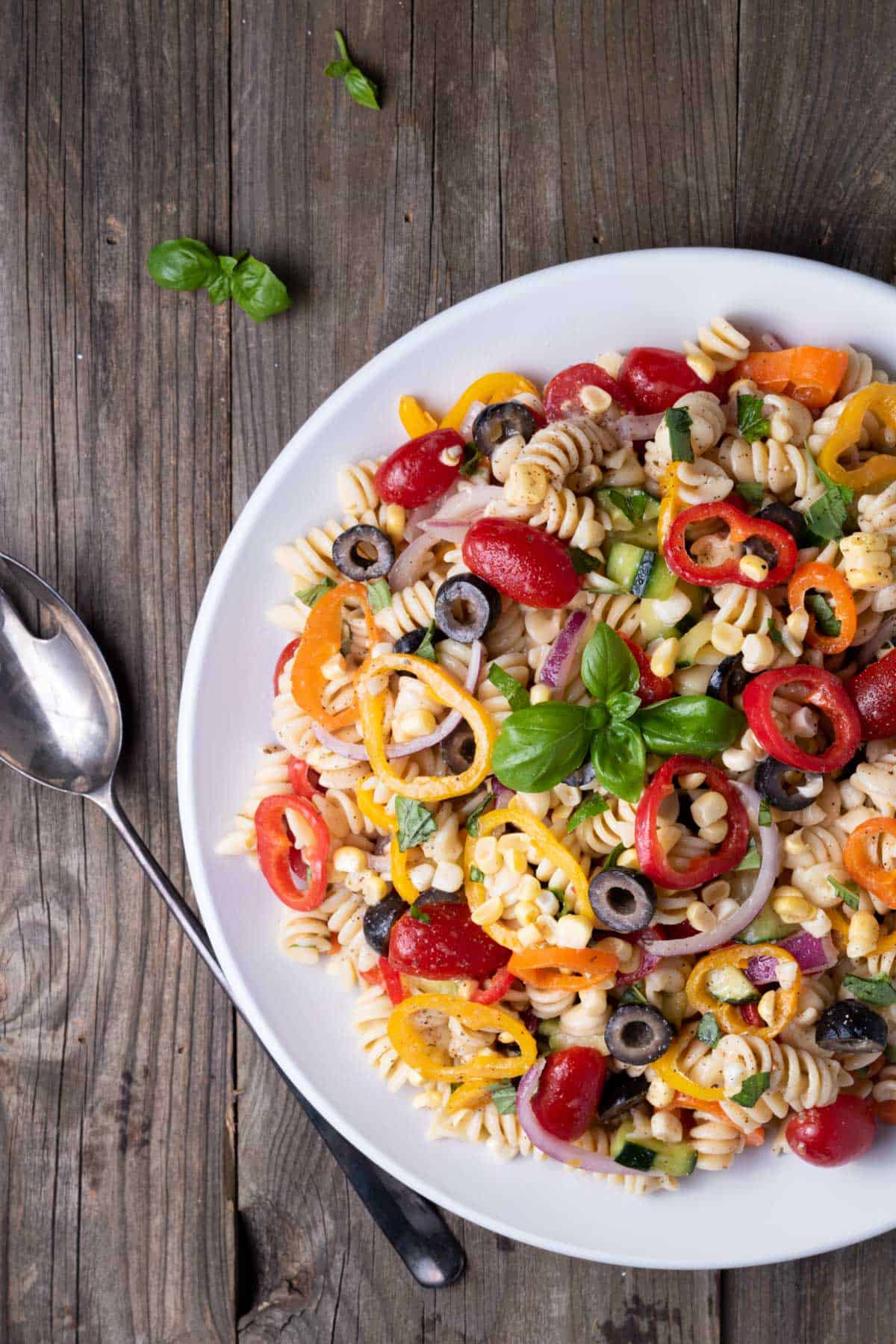 White plate of pasta salad on a rustic wooden table.