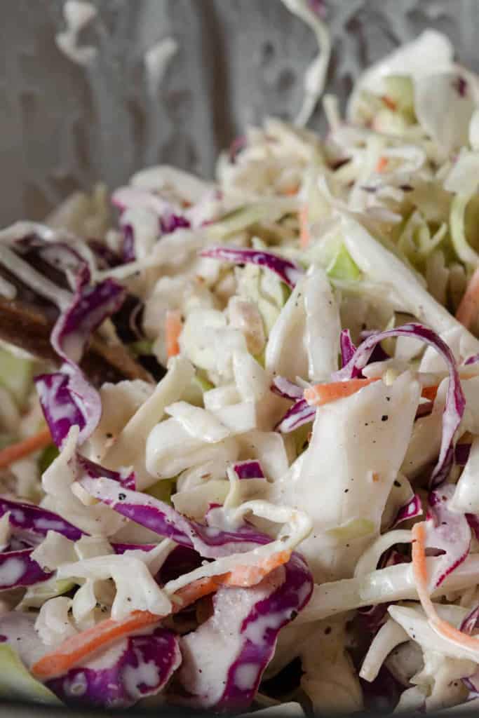 Close up view of a bowl of coleslaw with green cabbage, red cabbage, and carrots.