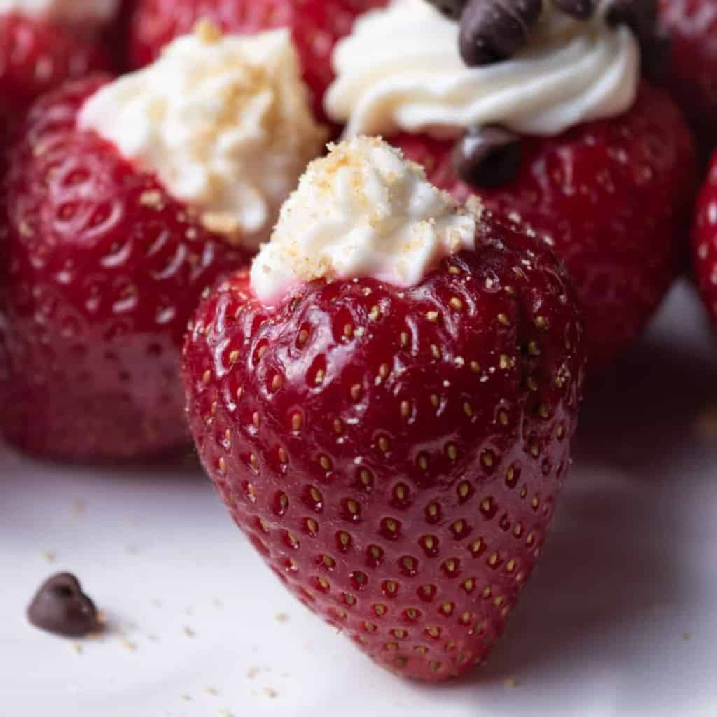 Cheesecake stuffed strawberries topped with chocolate chips and brown sugar.