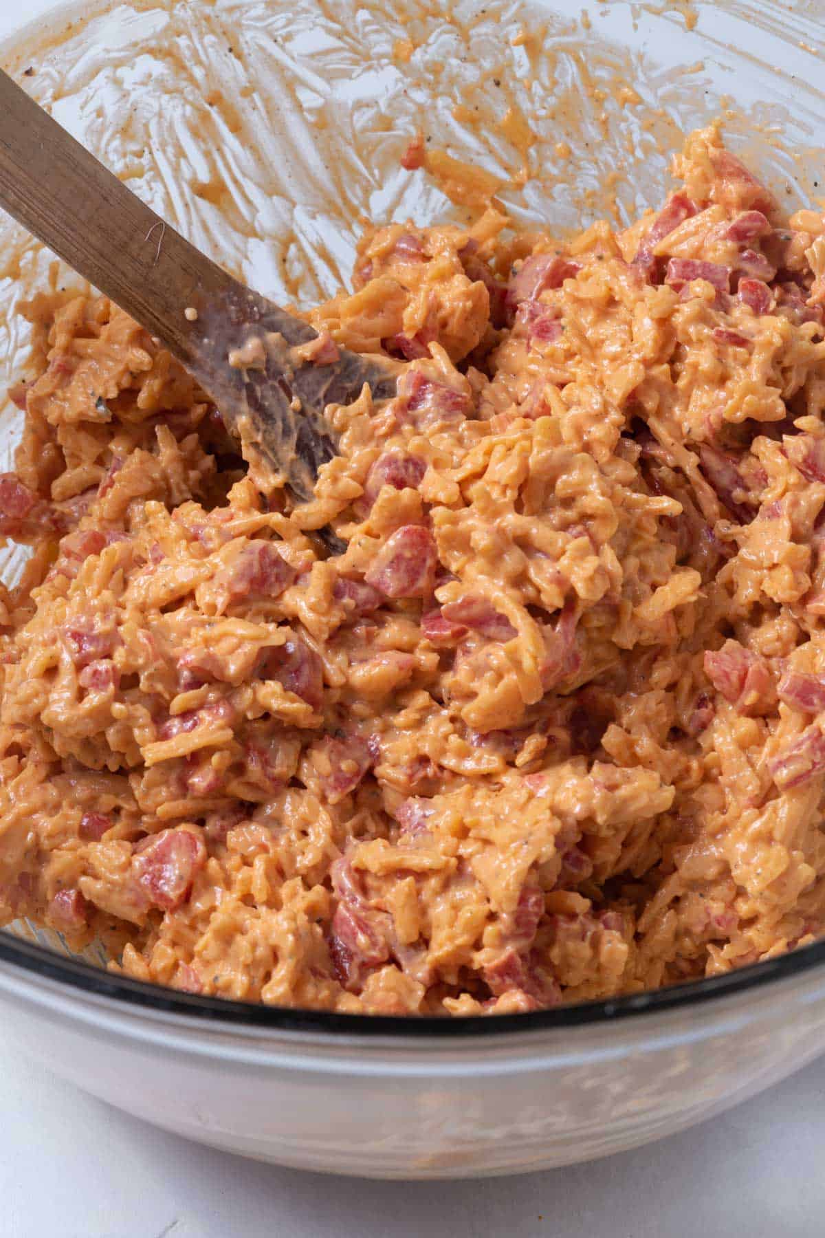 A bowl of pimento cheese with a wooden spoon.