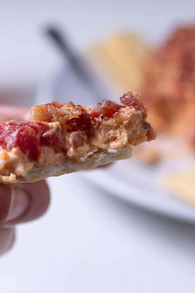 A bite of Southern style pimento cheese ball spread on a cracker.