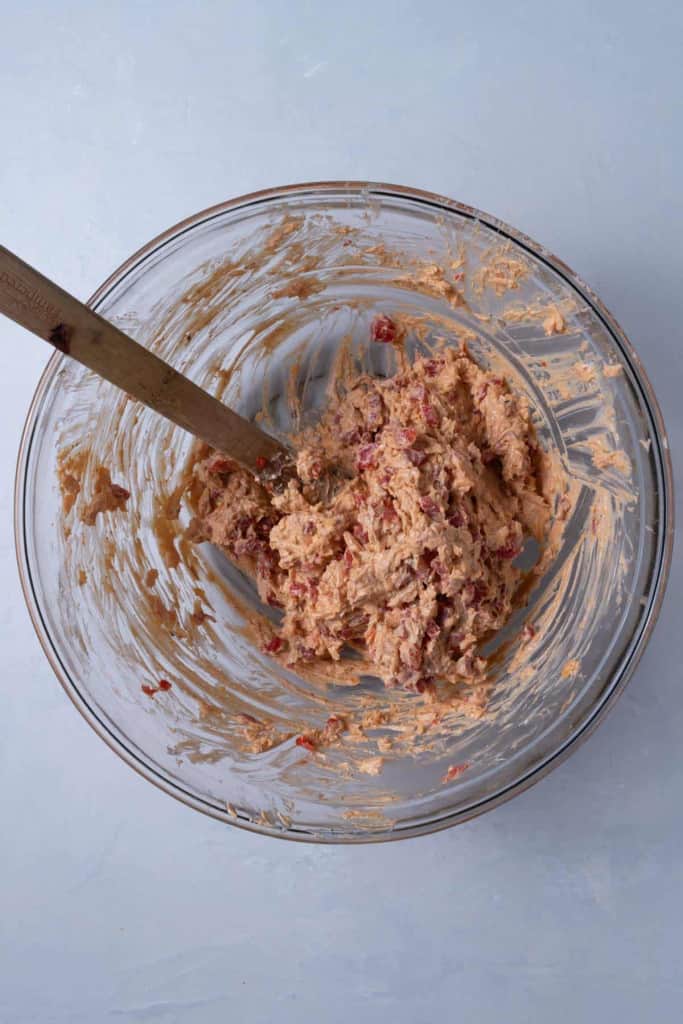A large glass bowl of pimento cheese getting mixed.