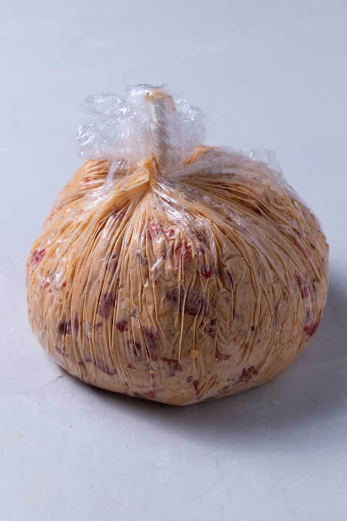 A cheese ball wrapped in plastic for shaping.