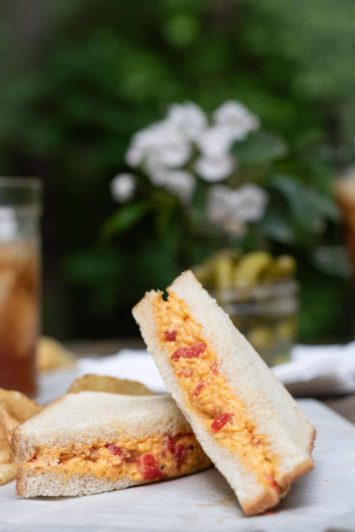 A lunch spread of pimento cheese, chips, pickles, and tea.