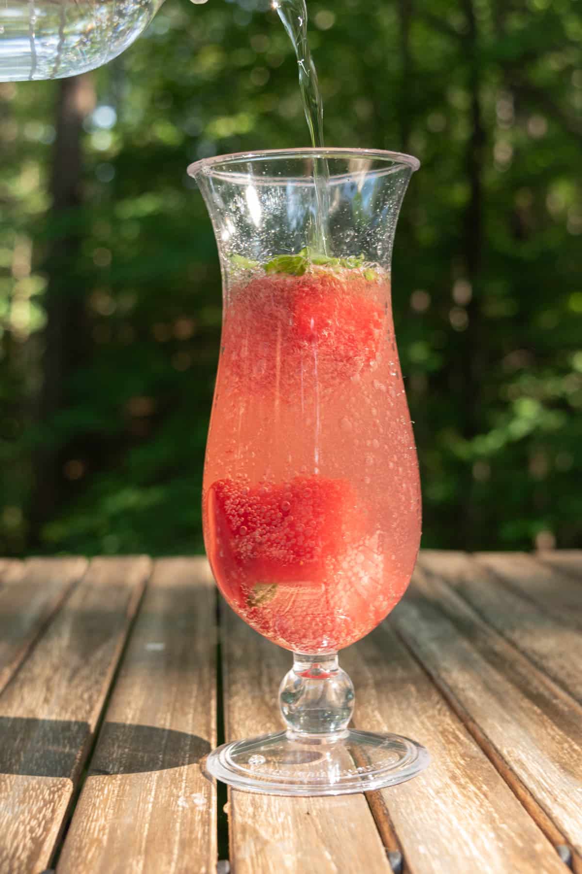 Sparkling water being poured into a strawberry basil mocktail.