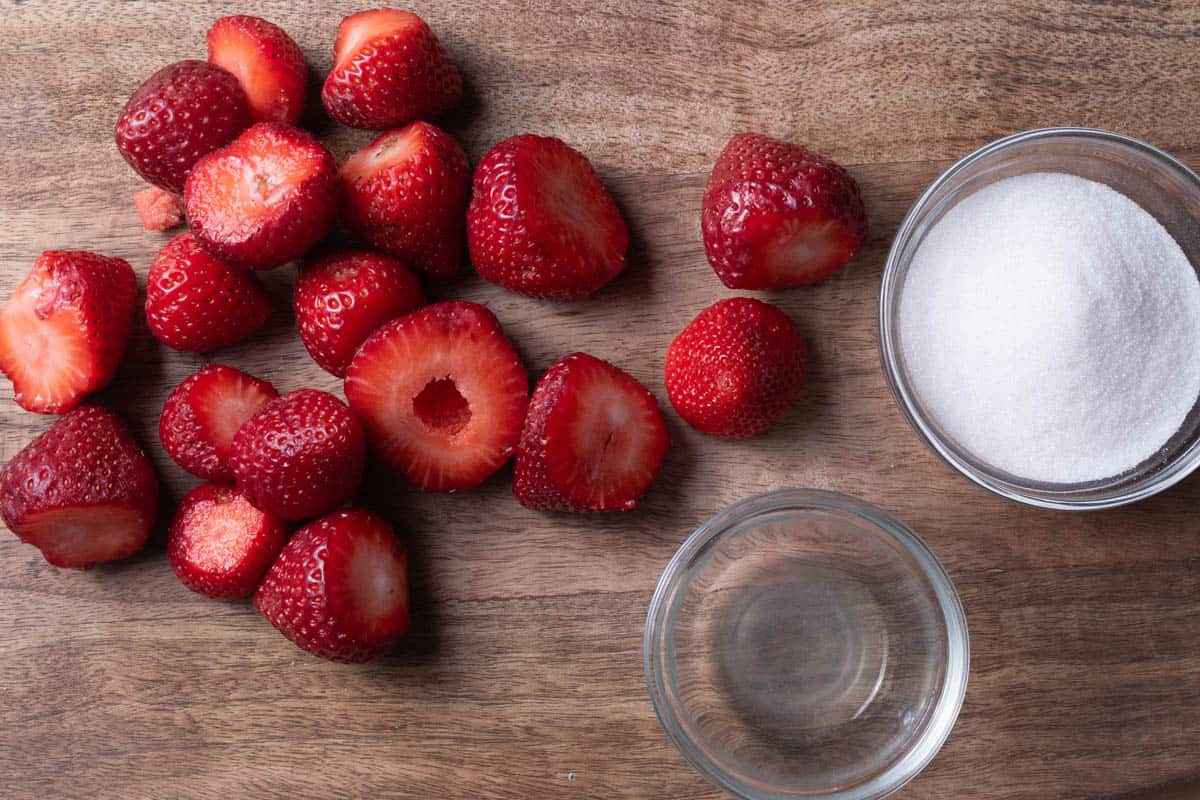 In season strawberries, sugar, and lemon juice on a wooden board.