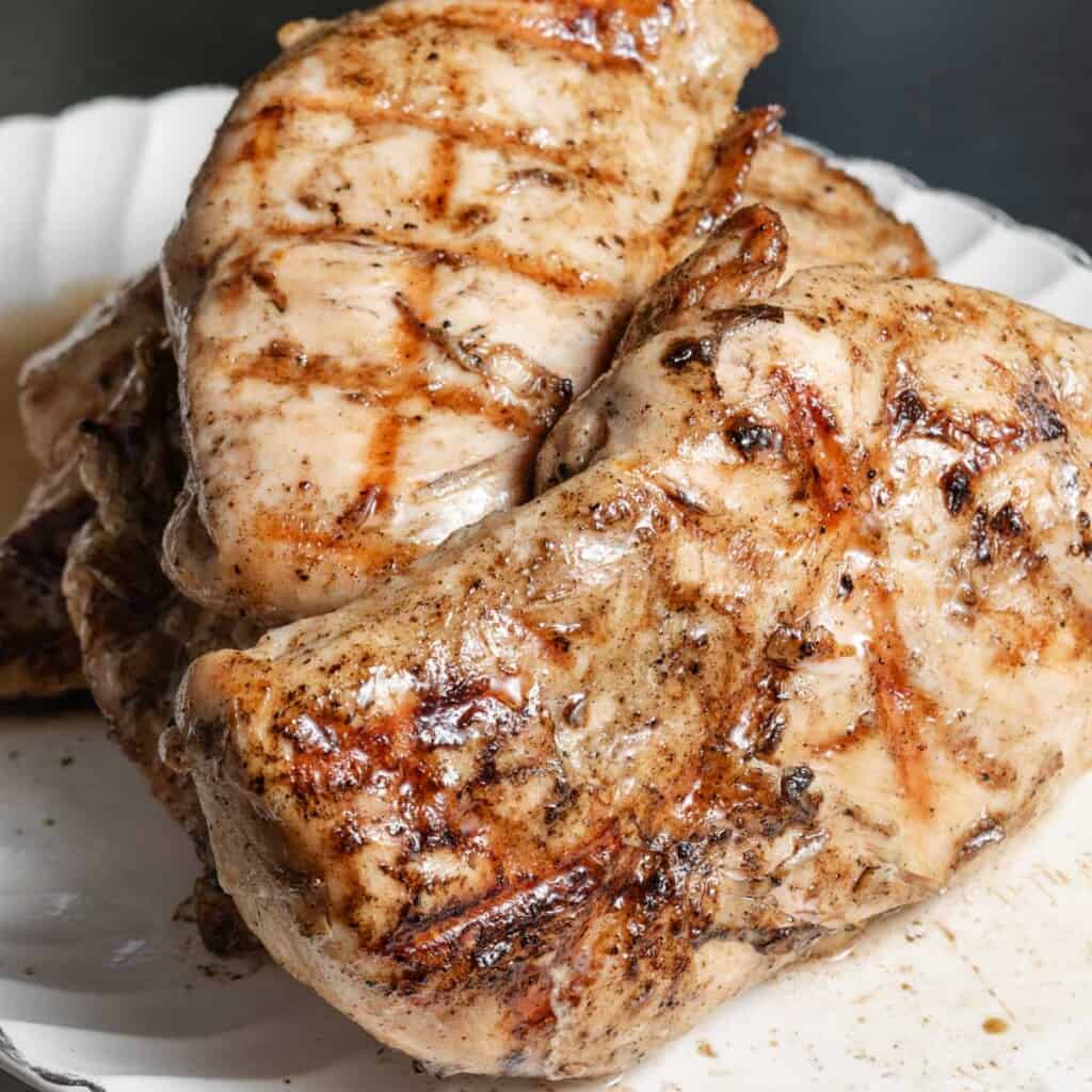 Grilled chicken breast on a white platter.