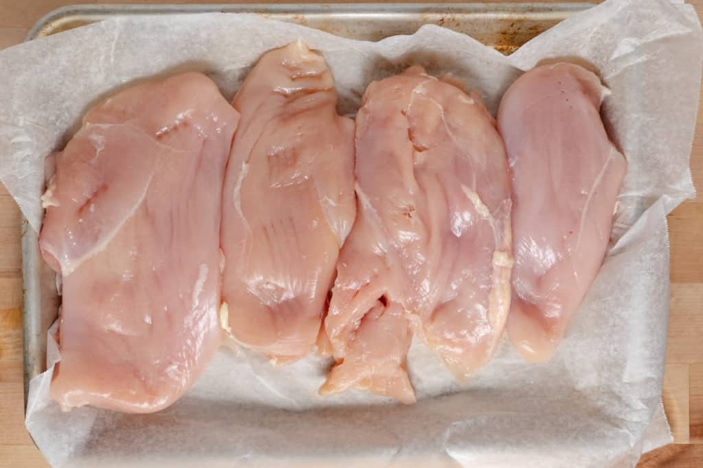 Raw chicken breast, pounded to a uniform thickness.