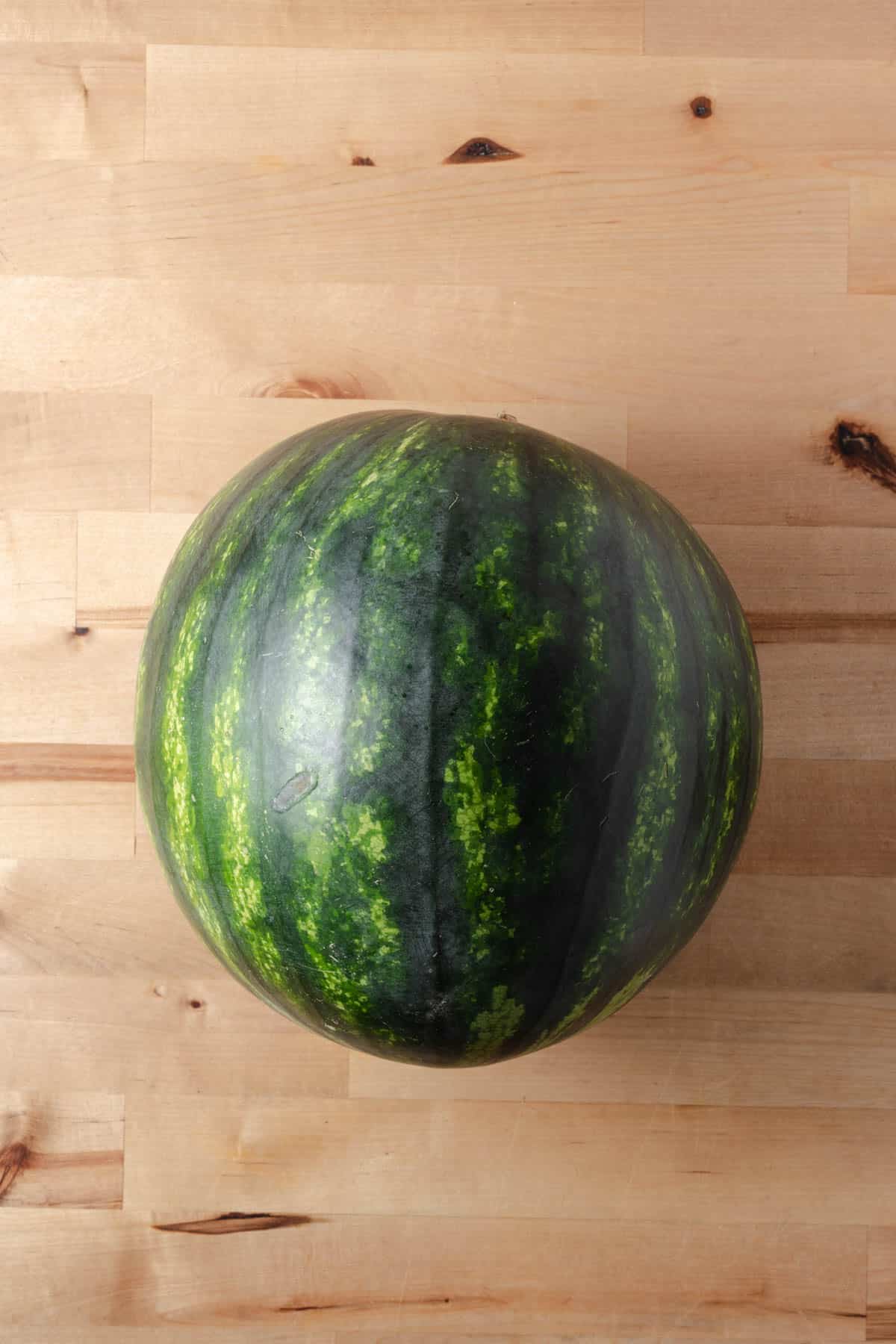A watermelon on a wooden board.