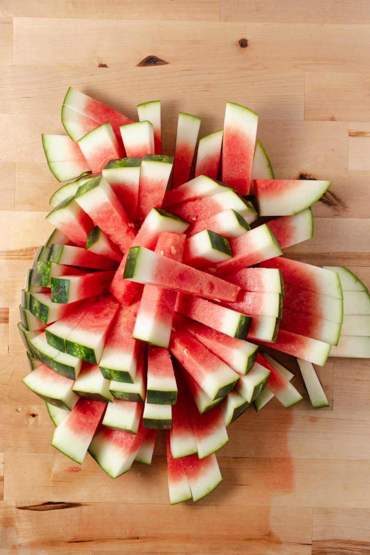 A pile of watermelon sticks with the rind on.