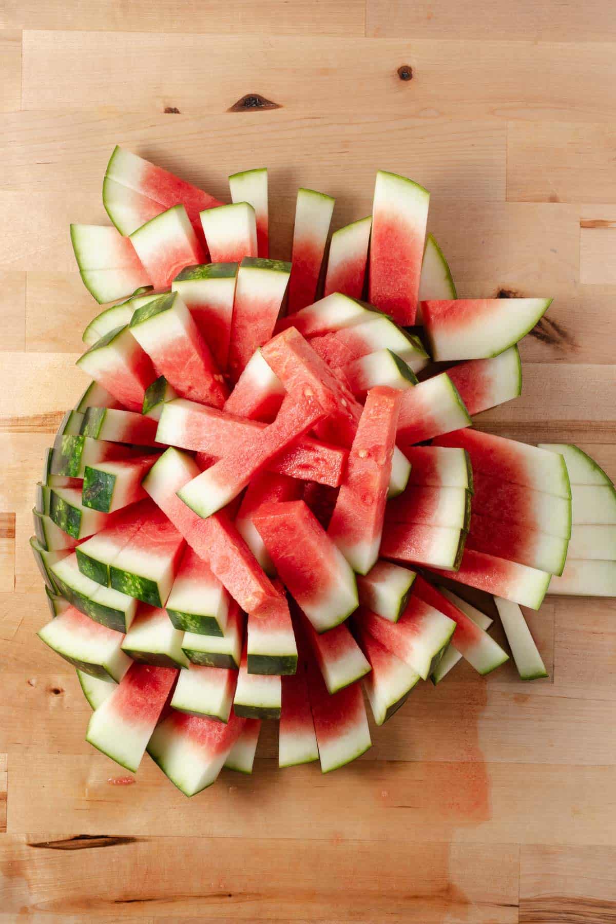 A pile of watermelon sticks with the rind on.