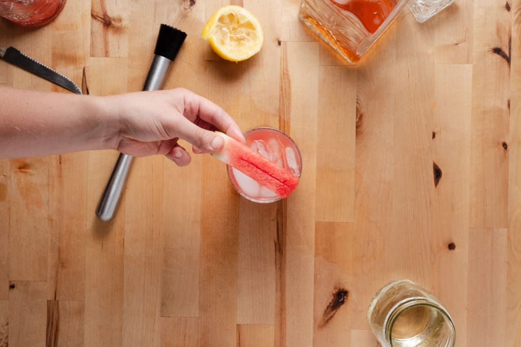 Showing a watermelon stick to garnish a cocktail.