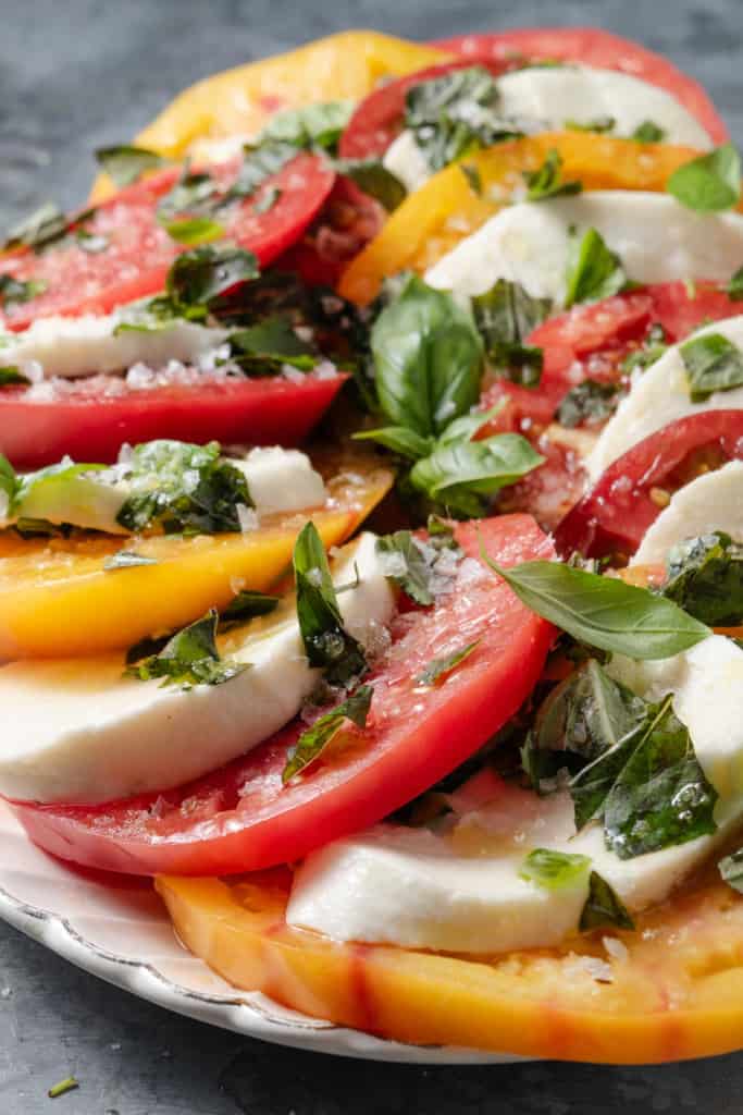 Heirloom tomato caprese salad with yellow, red, and Cherokee purple tomatoes on a platter.