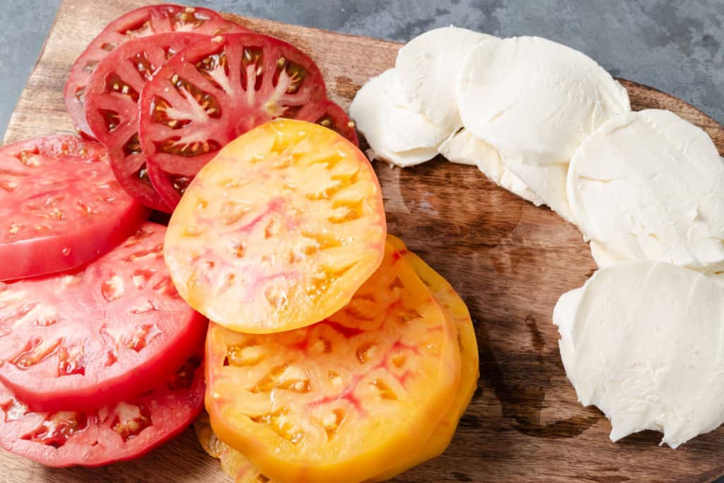 Sliced heirloom tomatoes and mozzarella on a cutting board.