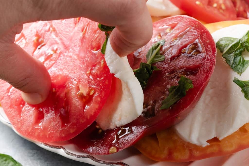 Tucking basil between slices of tomato and mozzarella.