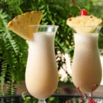 Freshly made pina coladas garnished with pineapple and cherry.