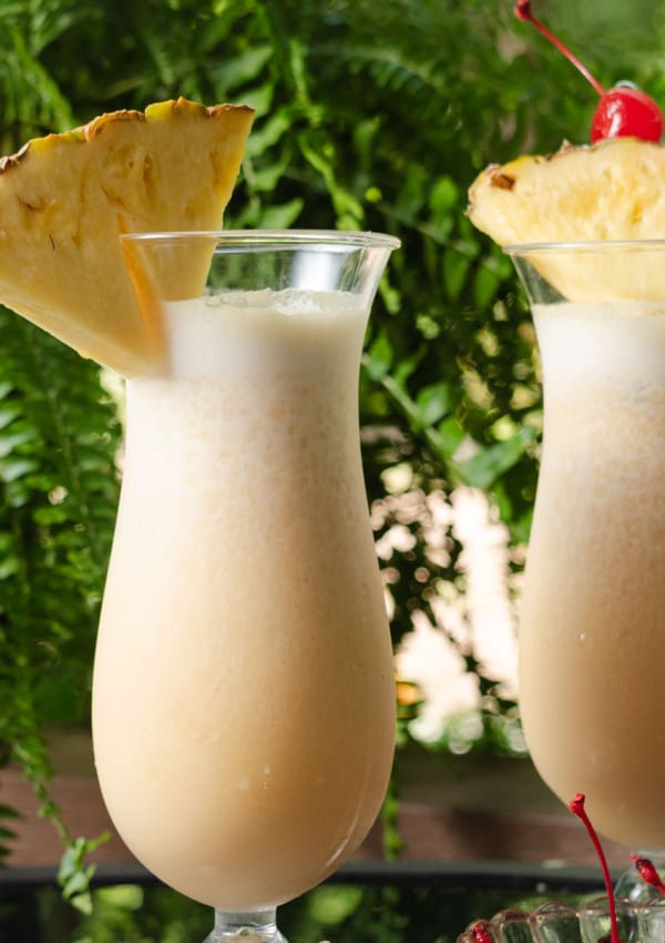 Freshly made pina coladas garnished with pineapple and cherry.