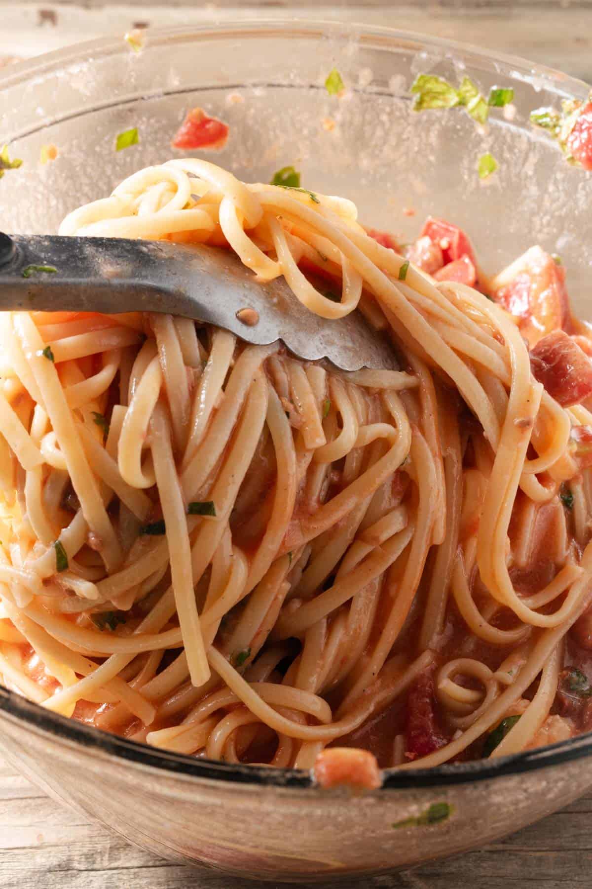 Tossing linguine in fresh tomato and basil sauce.