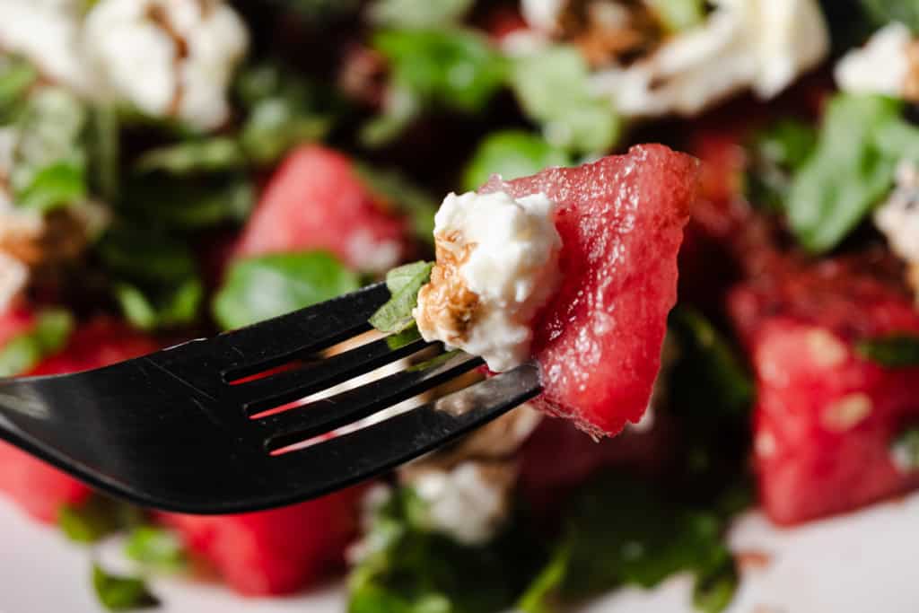 A bite of watermelon and burrata salad on a fork.