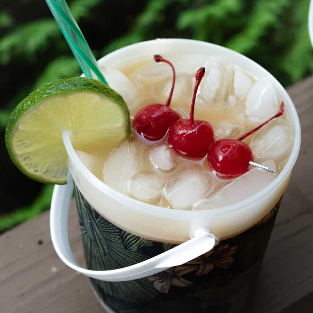 Caribbean fruit punch in a rum bucket with cherries and lime garnish.