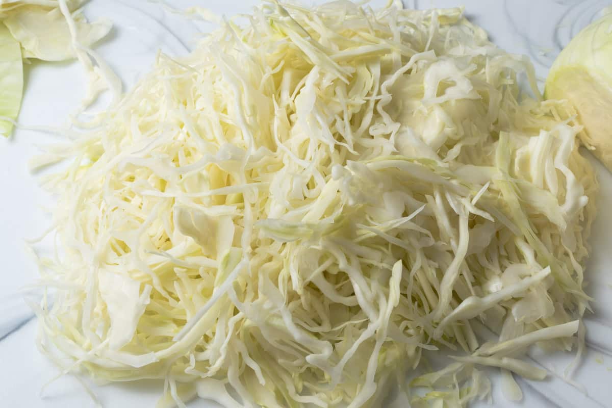 Finely shredded cabbage on a cutting board.