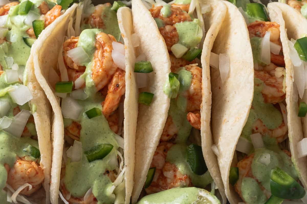 Chili lime shrimp tacos with cilantro lime crema, onions, and jalapenos on corn tortillas.