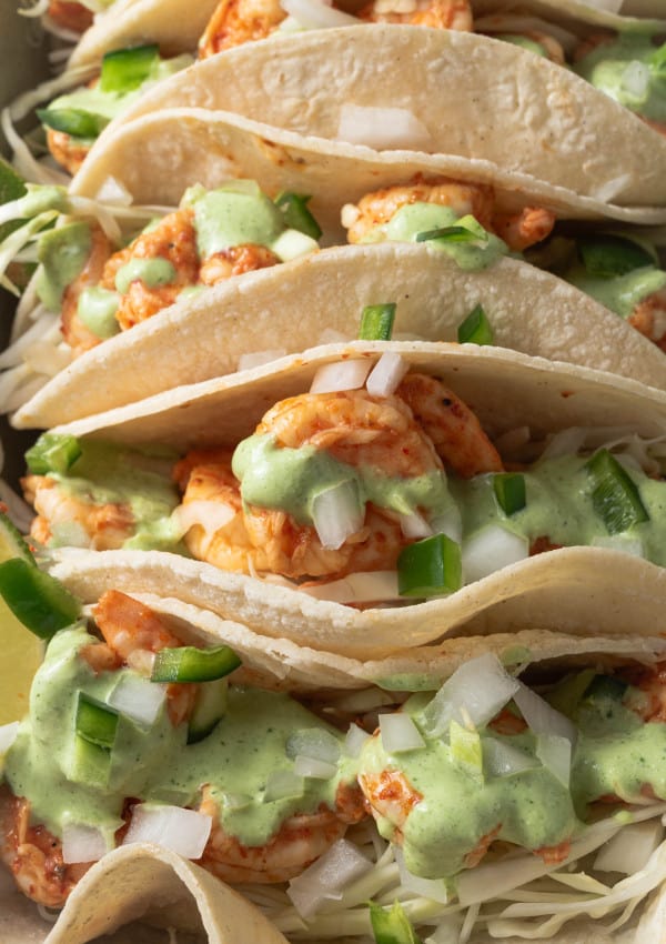 Chili lime shrimp tacos with cilantro lime crema, onions, and jalapenos on corn tortillas.
