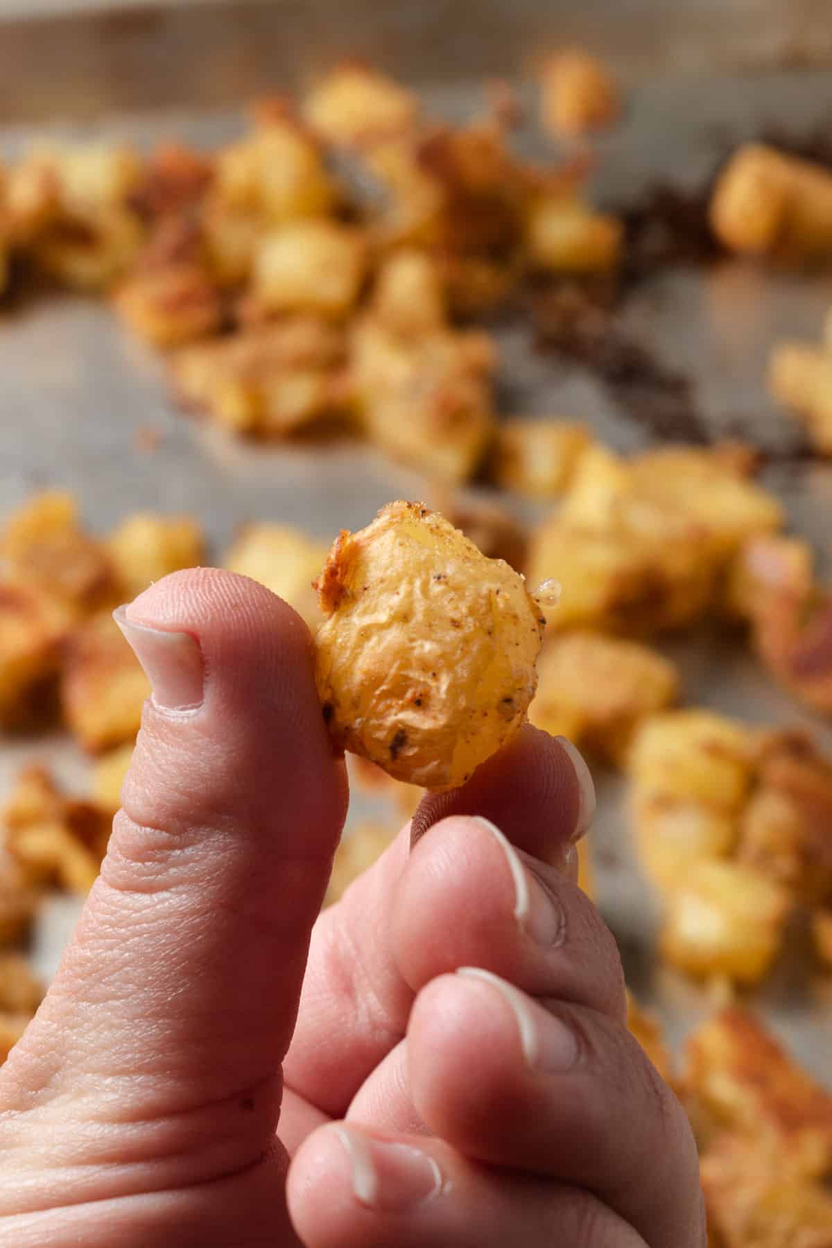 A hand holding a crispy potato bite.