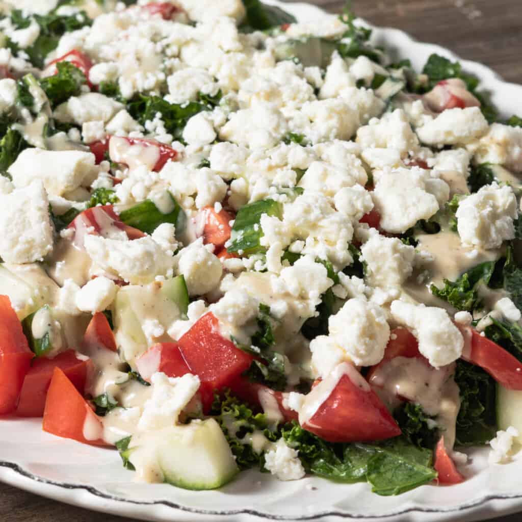 Kale salad with tahini lemon dressing, cucumber, tomato, and feta cheese.