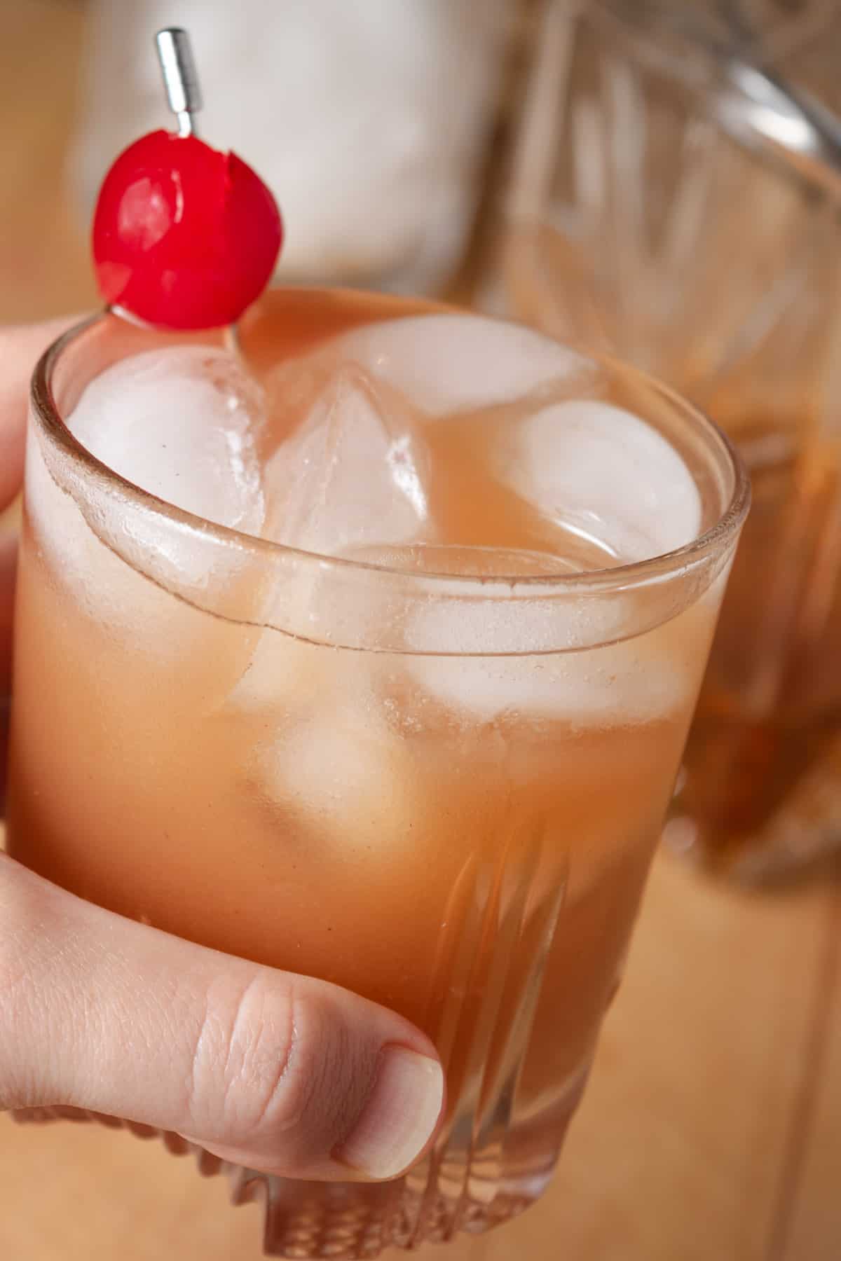 Apple butter bourbon cocktail on the rocks with a cherry.