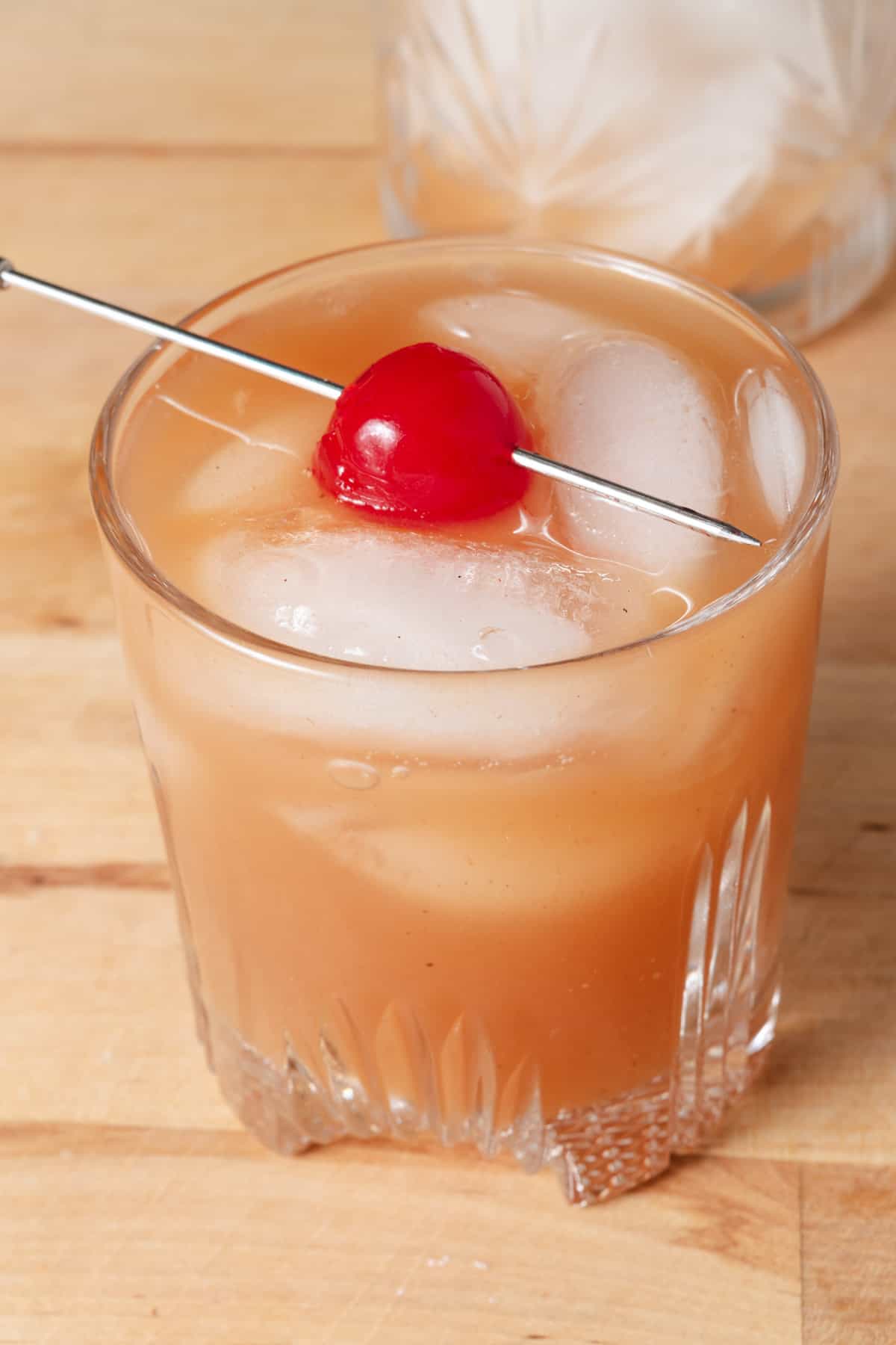 Apple butter bourbon cocktail on the rocks with a cherry.