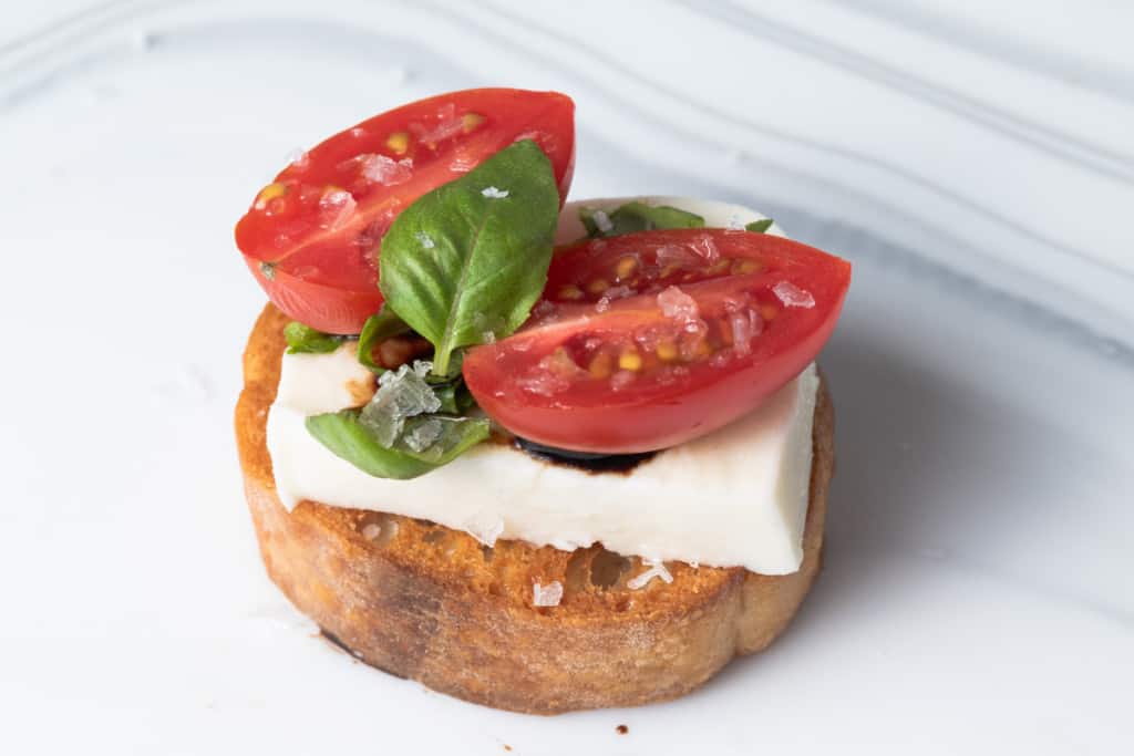 A caprese toast with balsamic, tomato, mozzarella, and basil.