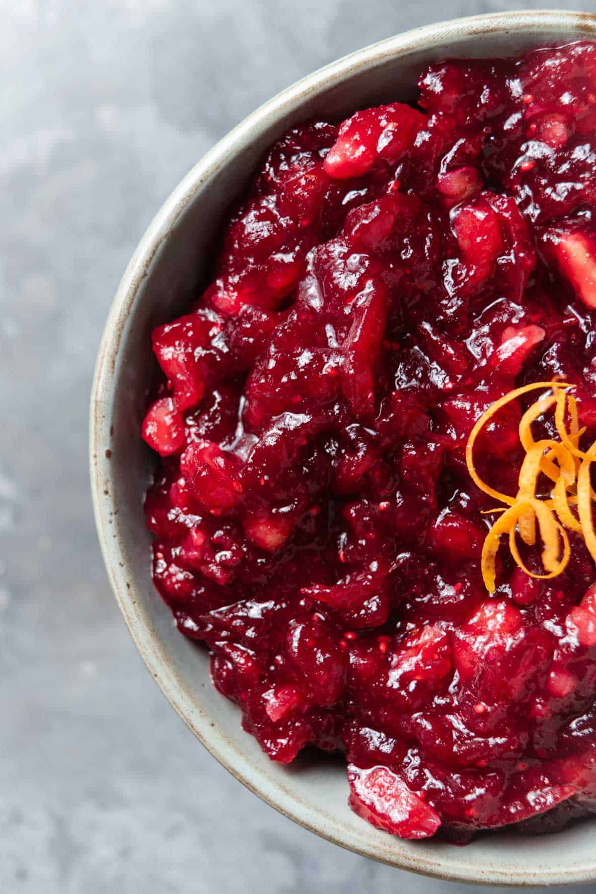 A bowl of whole berry cranberry sauce with mandarin oranges, walnuts, and orange zest.
