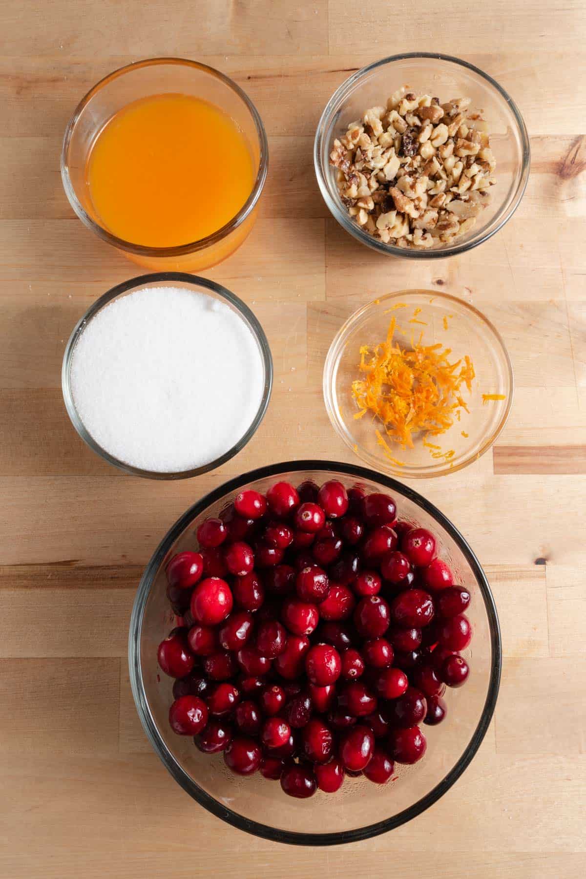 Mise en place for cranberry sauce with fresh cranberries, mandarin orange juice, mandarin orange zest, sugar, and walnuts.