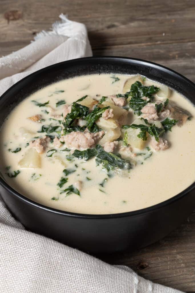 A bowl of creamy potato and kale soup with Italian sausage.