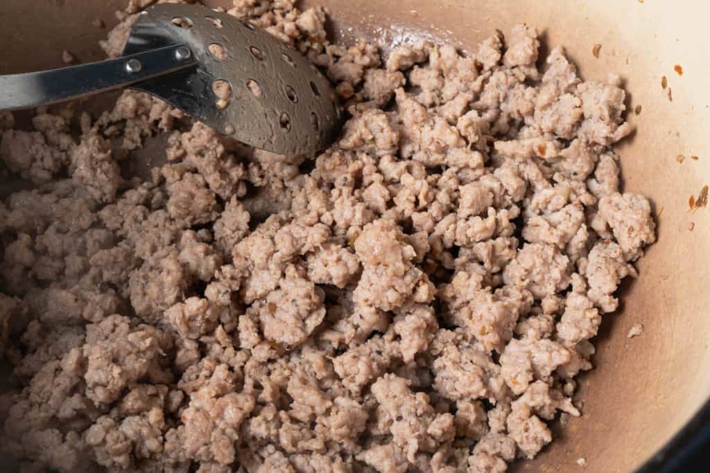 Browning Italian sausage crumbles in an enameled dutch oven.