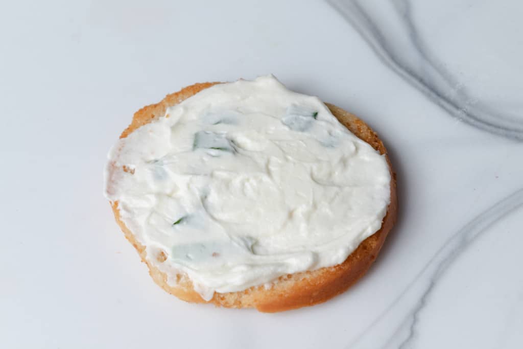 Whipped green onion cream cheese on a bagel crisp.