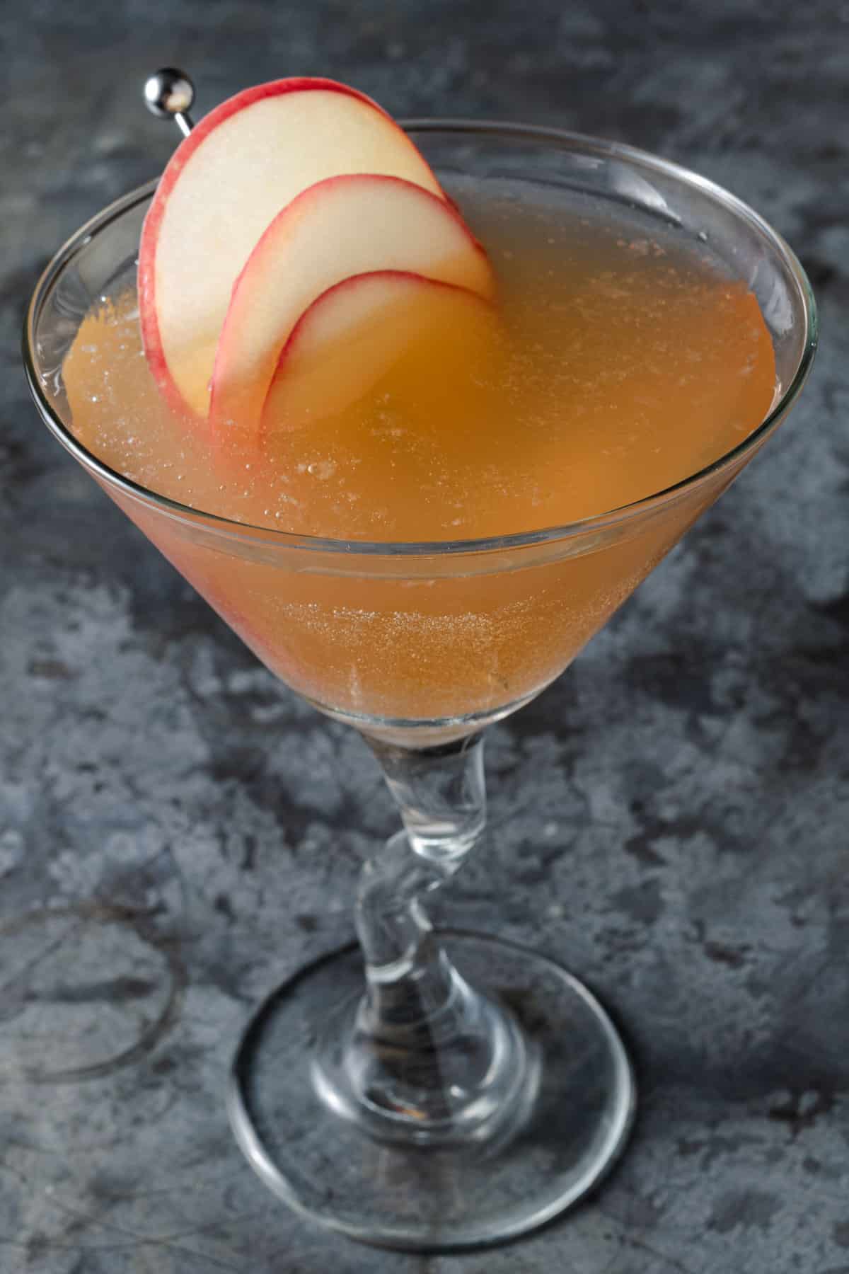 An apple cider martini with vodka and apple cinnamon stick garnish.