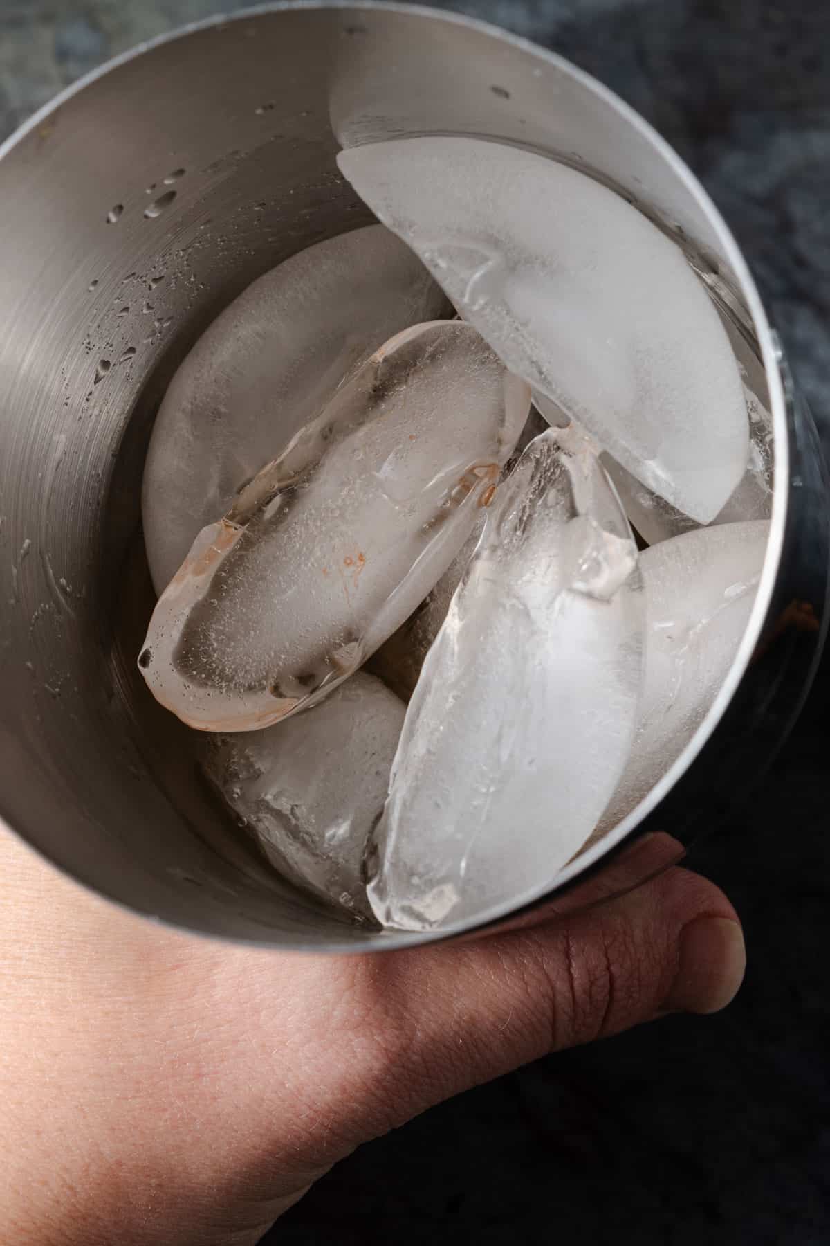 A cocktail shaker filled with ice, vodka, bitters, sweet vermouth, and fresh pressed apple cider.