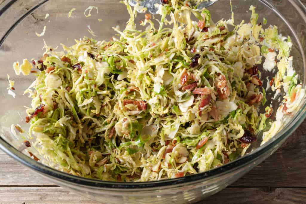 Tossing a brussel sprout salad with tongs.