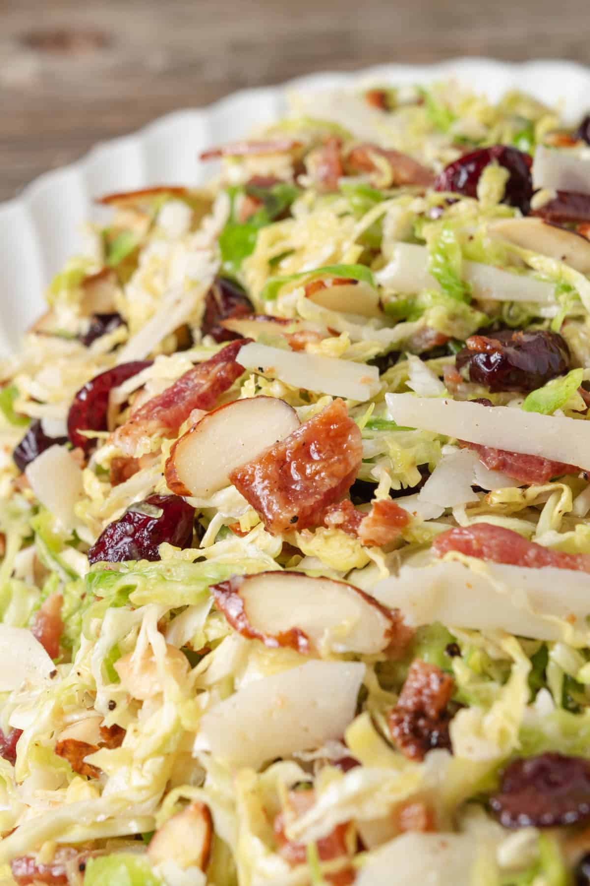 Brussel sprout salad made with shaved brussels sprouts, parmesan, cranberries, bacon, almonds, and a lemon vinaigrette.