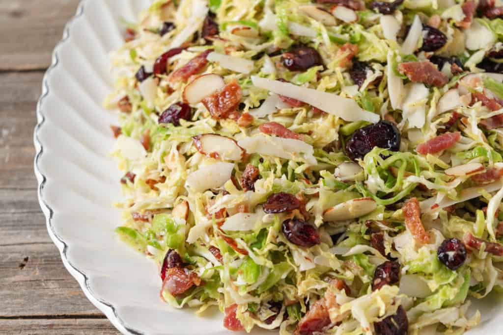 Brussel sprout salad made with shaved brussels sprouts, parmesan, cranberries, bacon, almonds, and a lemon vinaigrette.