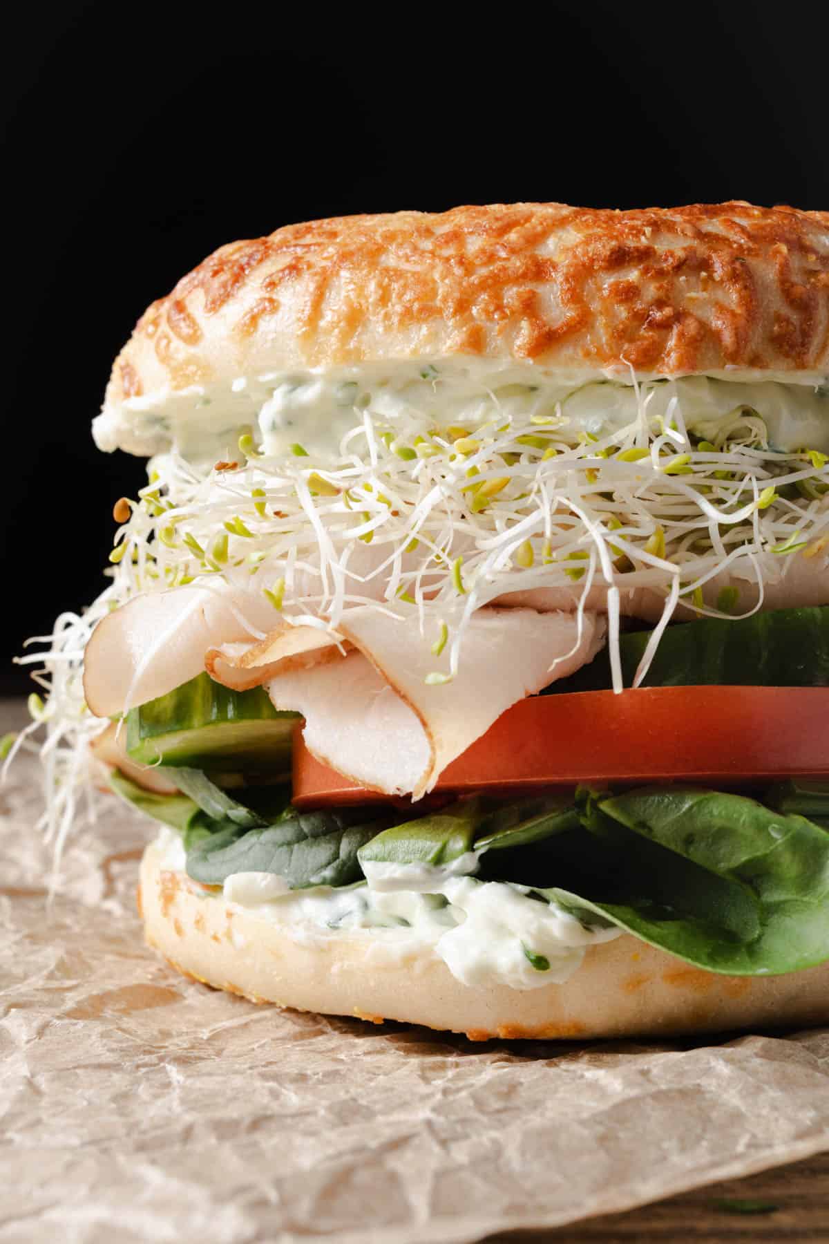 A turkey bagel sandwich with veggies and cream cheese.