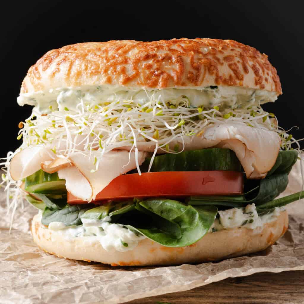 A turkey bagel sandwich with veggies and cream cheese.