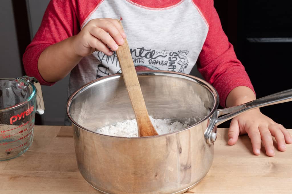 A preschooler stirring homemade play dough ingredients.
