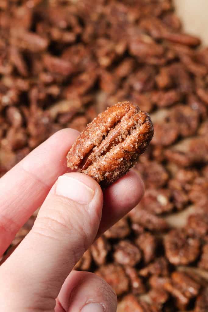 Holding a homemade roasted cinnamon sugar pecan.