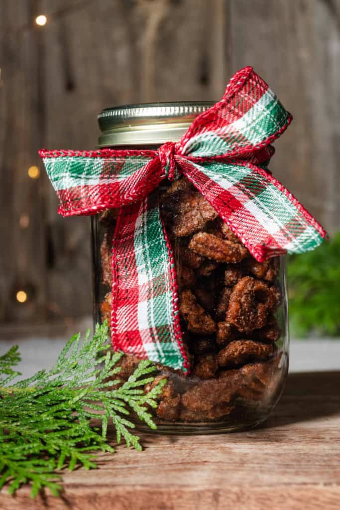 A jar of sweet and spicy candied pecans with a ribbon to give as a Christmas gift, a thank you, or a hostess gift.